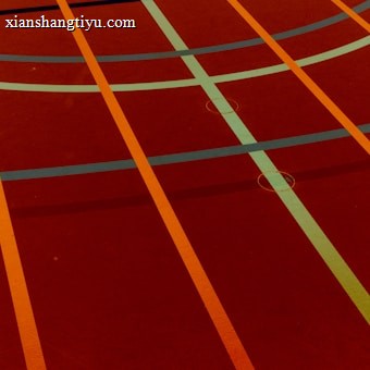 A sports court with intersecting lines in orange and blue, creating geometric patterns on a reddish-brown surface.